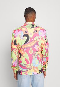 Camisa de manga larga multicolor con un audaz estampado floral en rosa, verde, naranja y negro. Hecha de una tela ligera y con un cuello.