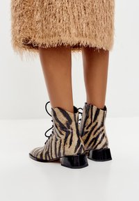 Veterschoenen tot de enkel in dierenprint met een gestructureerde afwerking, voorzien van een zwarte, stevige hak en een rits aan de zijkant.