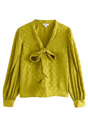 Green blouse with a v-neckline, tie-front detail, long puff sleeves, and polka dot pattern; made from lightweight, textured fabric.
