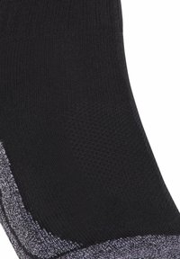 Primo piano di un calzino in tessuto nero e grigio con texture, caratterizzato da motivi a coste e in rete per traspirabilità e comfort.