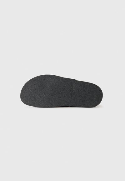 Schwarze Gummisohle mit strukturiertem Oberflächen, runder Zehenform und leichtem Absatz. Einfaches Design ohne sichtbare Muster oder Akzente.