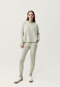 Ljusgrön sweattröja med sänkt axel, i kombination med matchande smalnade joggers. Bekväm tyg med en slät textur och fickor.