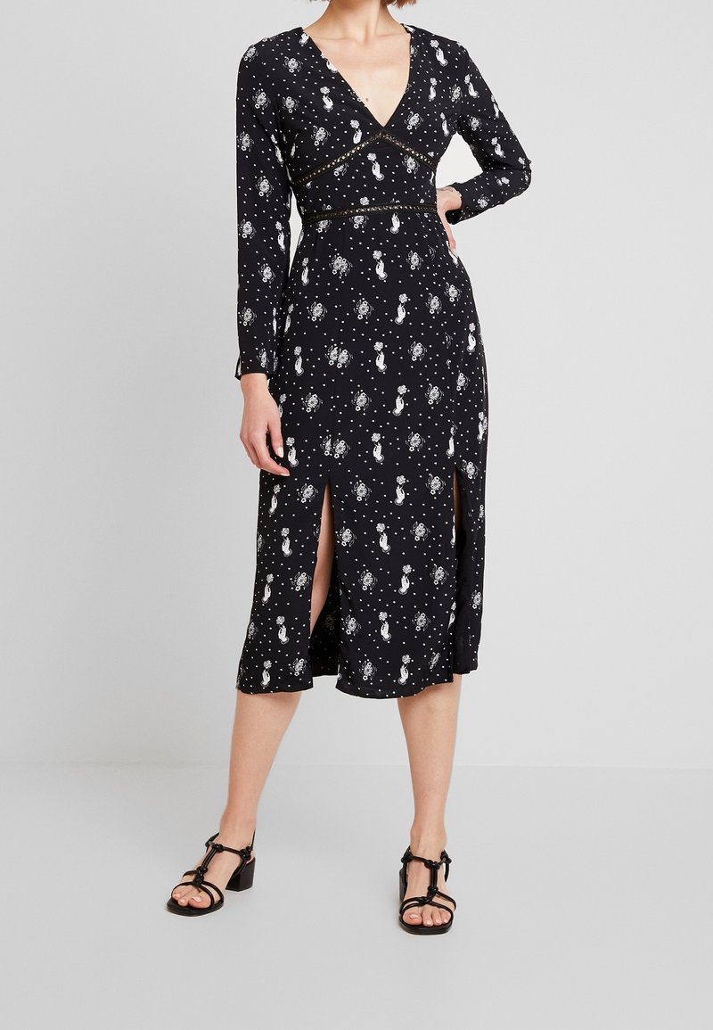 Černé šaty s překládaným designem, dlouhými rukávy a bočními rozparky. Mají bílý vzor nebeských motivů a jsou vyrobeny z hladké tkaniny.