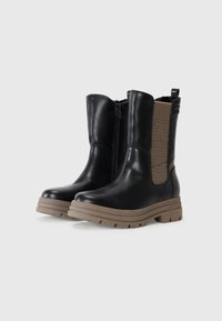 Bottines en cuir noir avec une fermeture éclair sur le côté, un panneau élastique beige et une semelle en caoutchouc beige. Présente une finition texturée et un design robuste.