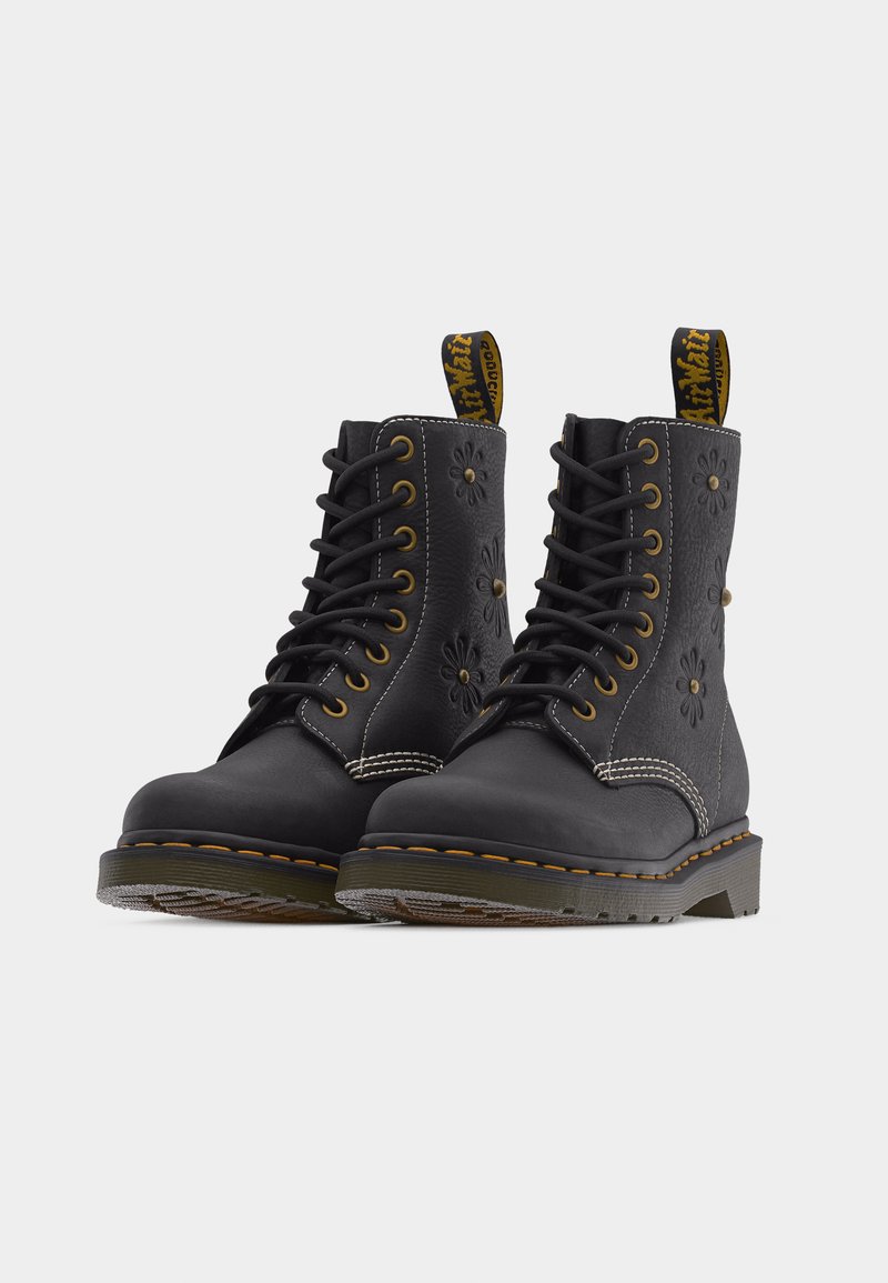 Bottes en cuir noir à lacets avec embossage floral, coutures jaunes et languettes de traction à logo sur semelles en caoutchouc robustes.