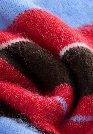 Punainen, sininen ja ruskea neulottu kangas, jossa on pehmeä tekstuuri, vaakasuoria raitoja ja vaihtelevaa paksuutta. Vähäisiä valkoisia korostuksia näkyvissä.