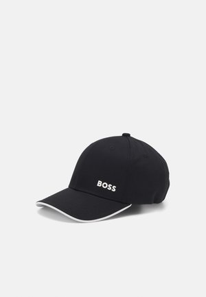 Črna kapa iz tkanine s ukrivljenim robom, ki ima spredaj belo logotip "BOSS" in bele dodatke ob robu.