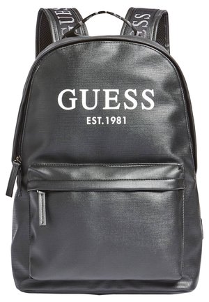 Sac à dos Guess noir avec poche avant zippée, surface texturée, et bretelles imprimées du texte "GUESS", étiqueté "EST. 1981" à l'avant.