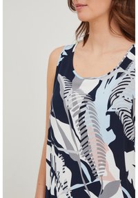 Top sin mangas de color azul marino con un patrón floral en tonos de azul claro, gris y rosa; tejido suave con un escote redondeado.