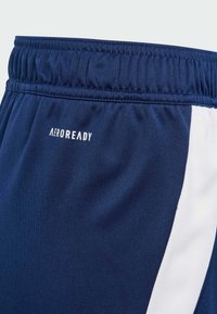 Tīra jūras zila elastīgā jostasvieta ar baltām sānu akcentiem un "AEROREADY" baltu logotipu priekšā. Gluda, viegla auduma.