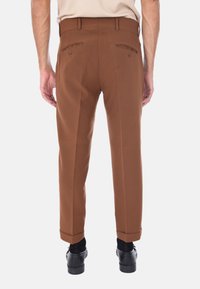 Pantaloni marroni su misura con design a gamba dritta, due tasche posteriori con bottoni e orli risvoltati. Realizzati in tessuto liscio, senza motivi.