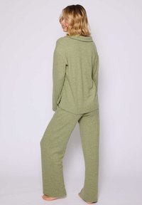 Ensemble de détente côtelé vert comprenant un haut à col replié et manches longues, associé à un pantalon droit.