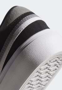 Mustikka ja harmaa lenkkikenkä, jossa on teksturoitu päällinen, valkoiset raidat, kumipohja sekä joustava ja pehmustettu muotoilu.