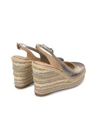 Metalen zilveren wedge sandalen met een ronde neus en een slingbackriem. Geweven jute en textuurpatronen versieren de wedge hak.