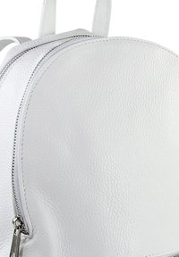 Weißer Leder-Rucksack mit runder Form, strukturiertem Oberflächenmaterial und einem auffälligen silbernen Reißverschluss-Detail an der Seite.