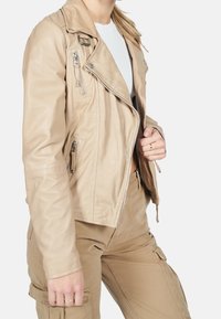 Béžová kožená motocyklová bunda se zipovými kapsami a zkráceným střihem. Má klopový límec a hladkou texturu.