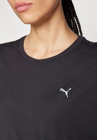 Svart sport-T-shirt med rund halsringning och korta ärmar, med en liten vit Puma-logotyp på vänstra bröstområdet.