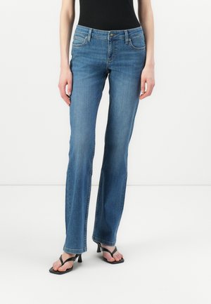 Blue denim jeans with a straight leg design, five pockets, a button-fly closure, and subtle stitching details, paired with black sandals.