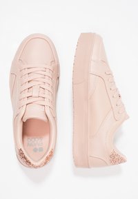 Ljusrosa sneakers med slätt material, rund tå, snördesign och texturerade detaljer vid hälen med glittrande inslag.