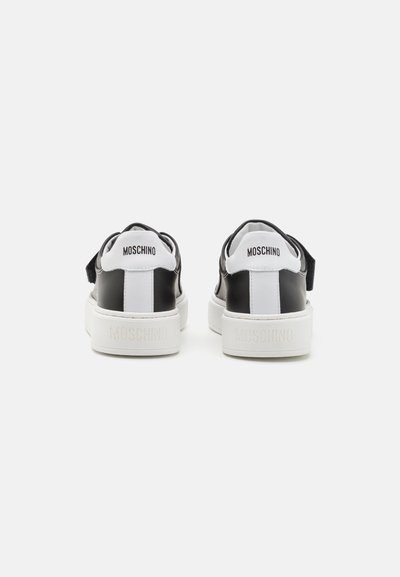 Zapatillas en blanco y negro con cuello acolchado, paneles en contraste y suelas de goma. Logo de "Moschino" grabado en el talón.