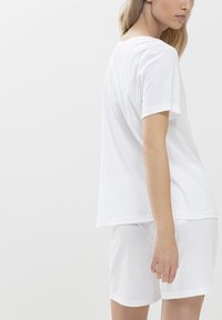 Witte katoenen t-shirt met een ronde hals en korte mouwen, gecombineerd met bijpassende shorts. Eenvoudig ontwerp, zachte textuur en een ontspannen pasvorm.