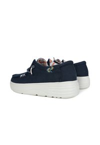 Marineblaue Segeltuchschuhe mit einer weißen Gummisohle, kontrastierenden Farbakzenten und gestickten Details, sowie einem gemusterten Innenfutter.