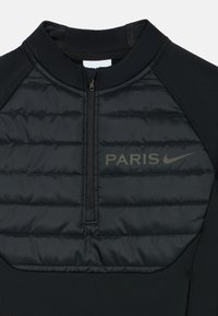 Svart atletisk topp med hög krage, halv dragkedja och quiltad frontpanel. Har "PARIS" och Nike-logotyp i matt grått. Slät textur.