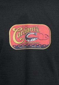 Camiseta negra de algodón con un gráfico de lata de pescado estilo vintage con acentos en rojo, amarillo y azul, mostrando "Sardinas picantes de Detroit de Carhartt".