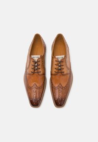 Pantofi din piele maro, cu șireturi, cu broderie intricate și detalii perforate, având vârful ascuțit și o textură fină.