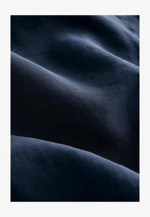 Granatowy materiał o gładkiej teksturze, z delikatnymi falami i zagnieceniami, które wskazują na lekki i elastyczny materiał.