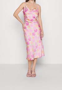Robe midi florale en soie avec des motifs rose, orange et vert. Dotée de bretelles fines ajustables et d'un décolleté drapé, légèrement évasée à l'ourlet.
