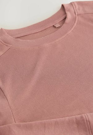 Vaaleanpunainen pitkähiha, jossa on ribbitetty pinta, pyöreä pääntie ja kontrastiväriset saumat, valmistettu pehmeästä kankaasta mukavuutta varten.