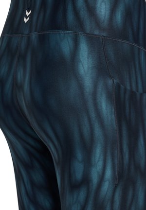 Hoge taille legging in donkerblauw met een gestructureerd, golvend patroon. Heeft een klein logo bij de tailleband en een zijvak.