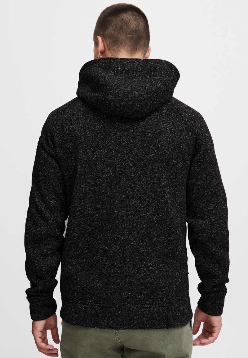 Black flecked hoodie with a textured finish, featuring a lined hood, long sleeves, and a relaxed fit. Additional detail includes a small side zip.