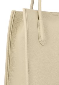 Beige leren totebag met een textuur oppervlak, twee handvatten en een gestructureerde vorm met naadloos stikwerk en minimale hardware.