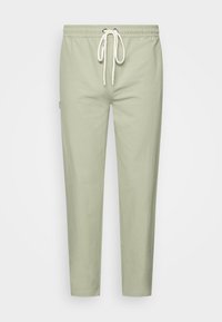 Ljusgröna sweatpants med elastisk midja, justerbar snörning och smal passform. Tillverkade av mjukt tyg, utan synliga mönster eller accenter.