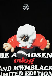 La camiseta negra presenta una figura de dibujo animado con una capucha blanca texturizada y mangas rojas, complementada con texto prominente en blanco y rojo.