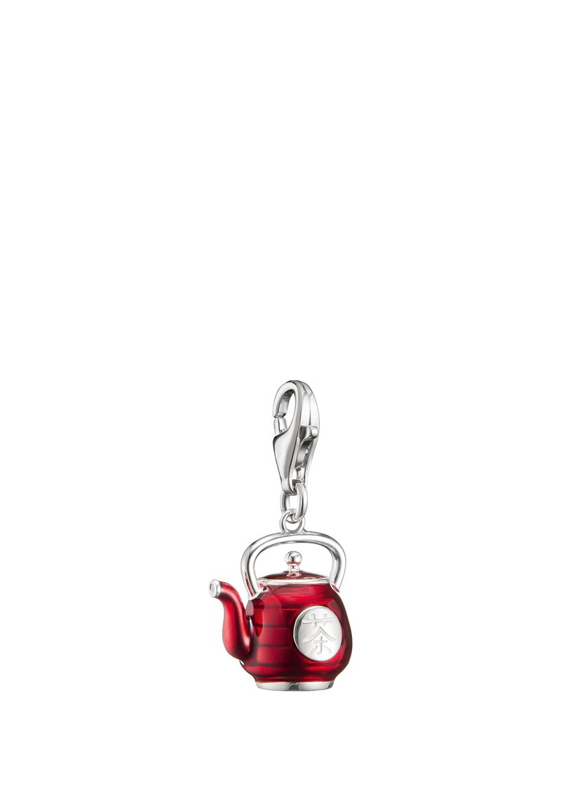 Small red teapot charm with silver handle, spout, and clasp, featuring a silver circular emblem with an engraved symbol.