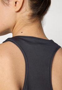 Must have musta, kaelusekujulise, suletud kaelusega must sportlik särk on sileda tekstuuriga, õmmeldud detailidega ja reljeefse logoga seljal.