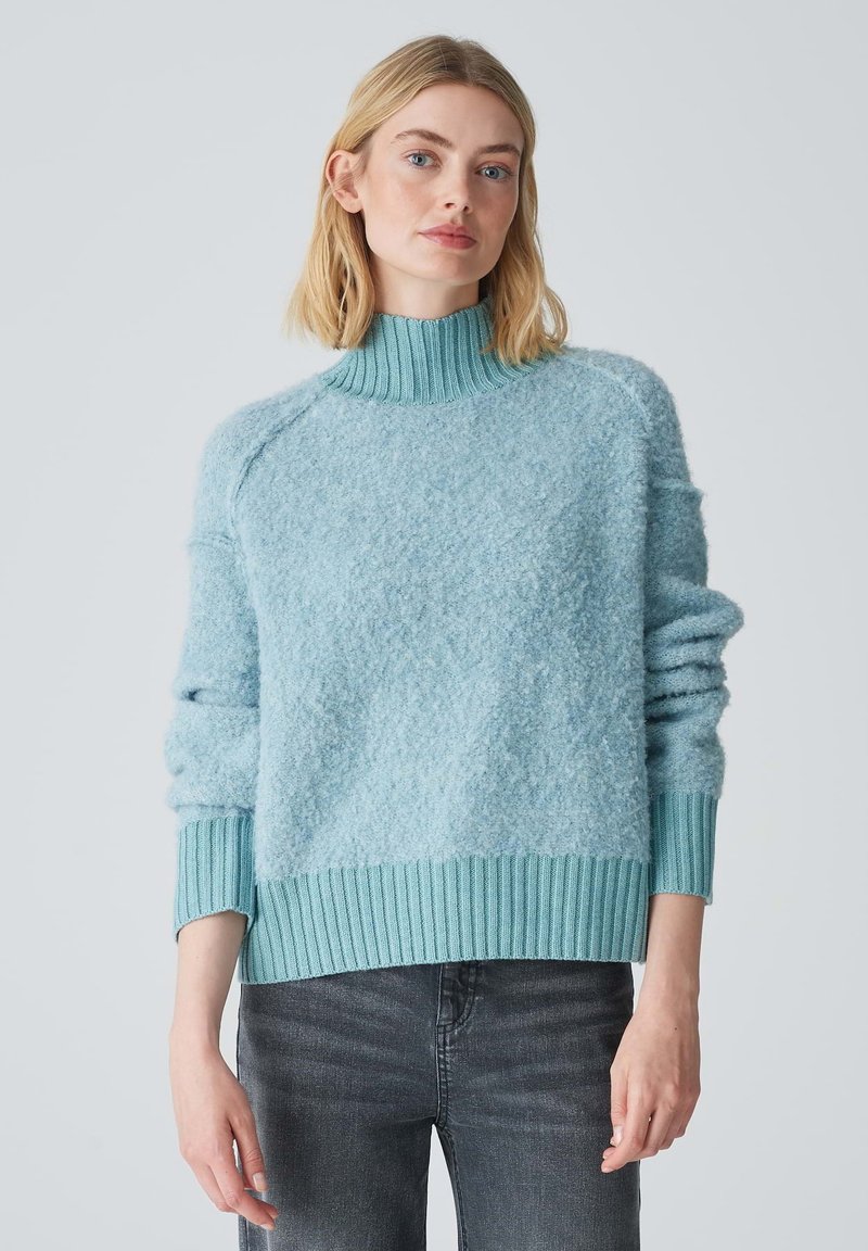 Light blue sweater with a textured, fluffy finish. High ribbed collar and cuffs, featuring a slightly loose fit and ribbed hemline.