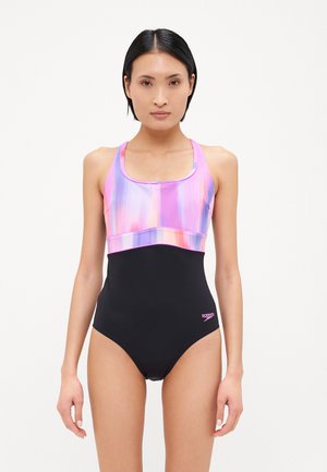Maillot de bain une pièce avec une partie supérieure dégradé violet et rose et un bas noir uni. Fabriqué en matière extensible pour maillots de bain.