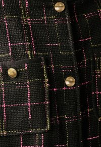 Giacca nera con texture, caratterizzata da un pattern a quadri rosa e verde, con bottoni color oro e due tasche frontali.