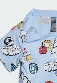 Camisa de manga corta de color azul claro con divertidos diseños de dibujos animados, incluyendo estrellas, flores y un balón de fútbol. Cierre a presión en el cuello.