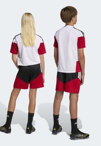 Red and white athletic apparel set, featuring short-sleeve shirt and shorts with black accents, made from lightweight material.
