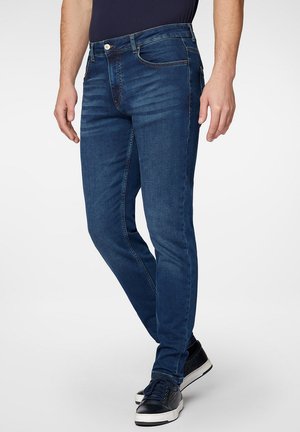 Jeans dżinsowe w ciemnoniebieskim kolorze o dopasowanym kroju, z zamkiem błyskawicznym i zapięciem na guzik. Dodatki obejmują kieszenie z przodu oraz subtelne efekty przetarcia.