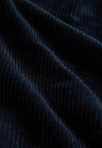Tissu côtelé bleu marine avec une texture ribbed verticale, doux et moelleux, présentant de profonds sillons dans un motif ondulé.