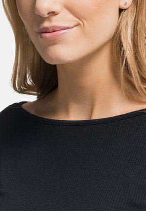 Schwarzes, geripptes Top mit weitem Ausschnitt, enganliegend. Sichtbare kleine Steckerohrringe. Glatte Hautfarbe, lange wellige blonde Haare auf einer Seite.