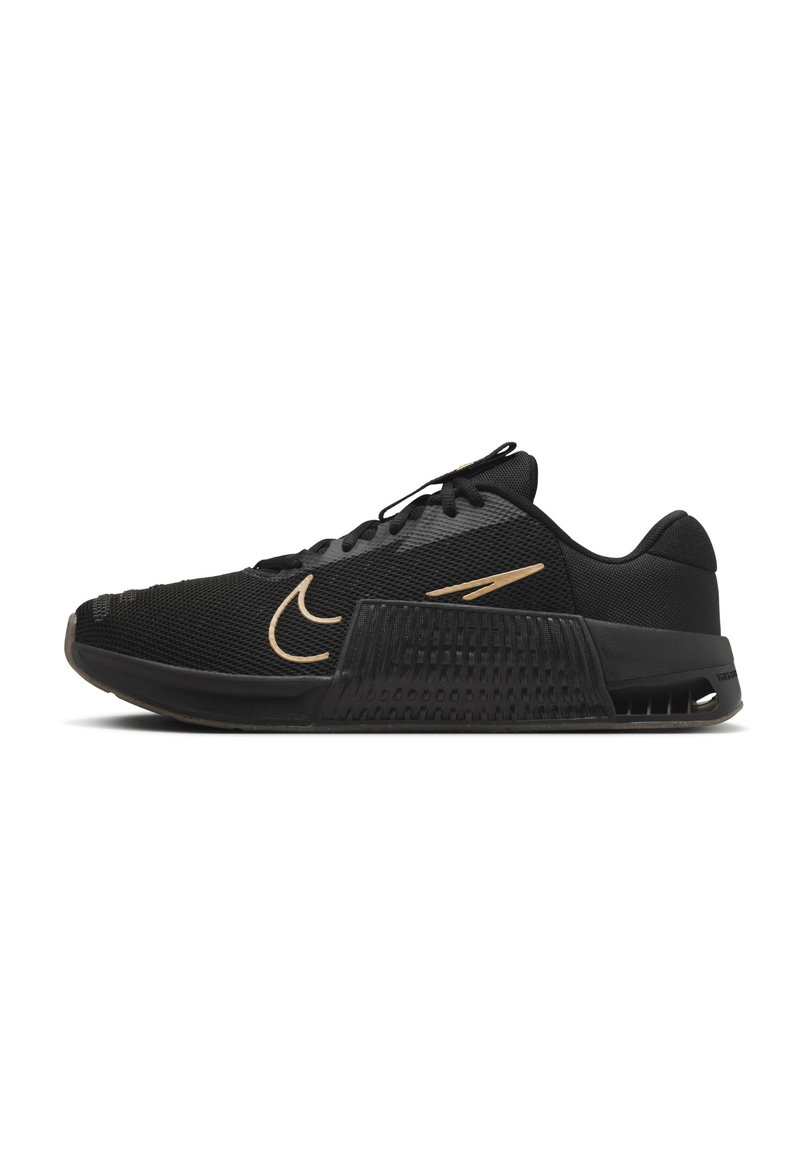 Scarpe sportive nere con tomaia in rete testurizzata, baffo dorato e suola rigida e patterned. Presentano un design con lacci e un tallone imbottito.