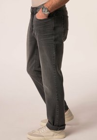 Ciemnoszare dżinsy o prostym kroju, z widocznymi przednimi i tylnymi kieszeniami oraz podwiniętymi nogawkami. Połączone z jasnymi trampkami.