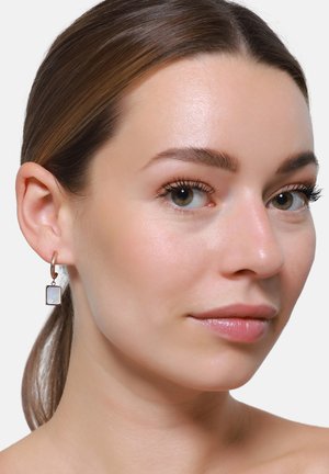 Boucles d'oreilles créoles en or rose avec des accents de pierres blanches rectangulaires, surface lisse, conception légère et un éclat subtil.